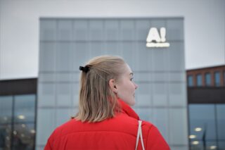 Nuori nainen Aalto-yliopiston rakennuksen edessä