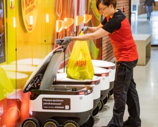 A woman loading groceries onto a transport robot